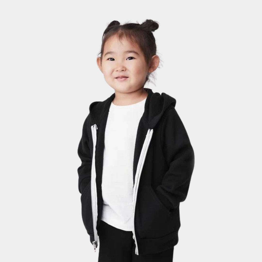 toddler smiling at camera with jacket on and hands in pockets