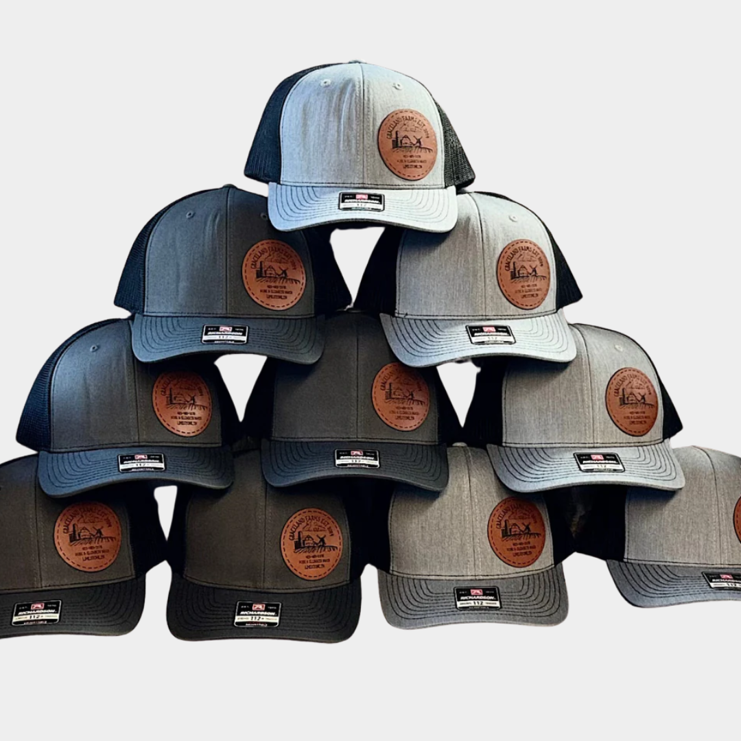 pile of black and grey and dark grey and black hats with circular leather patch logo