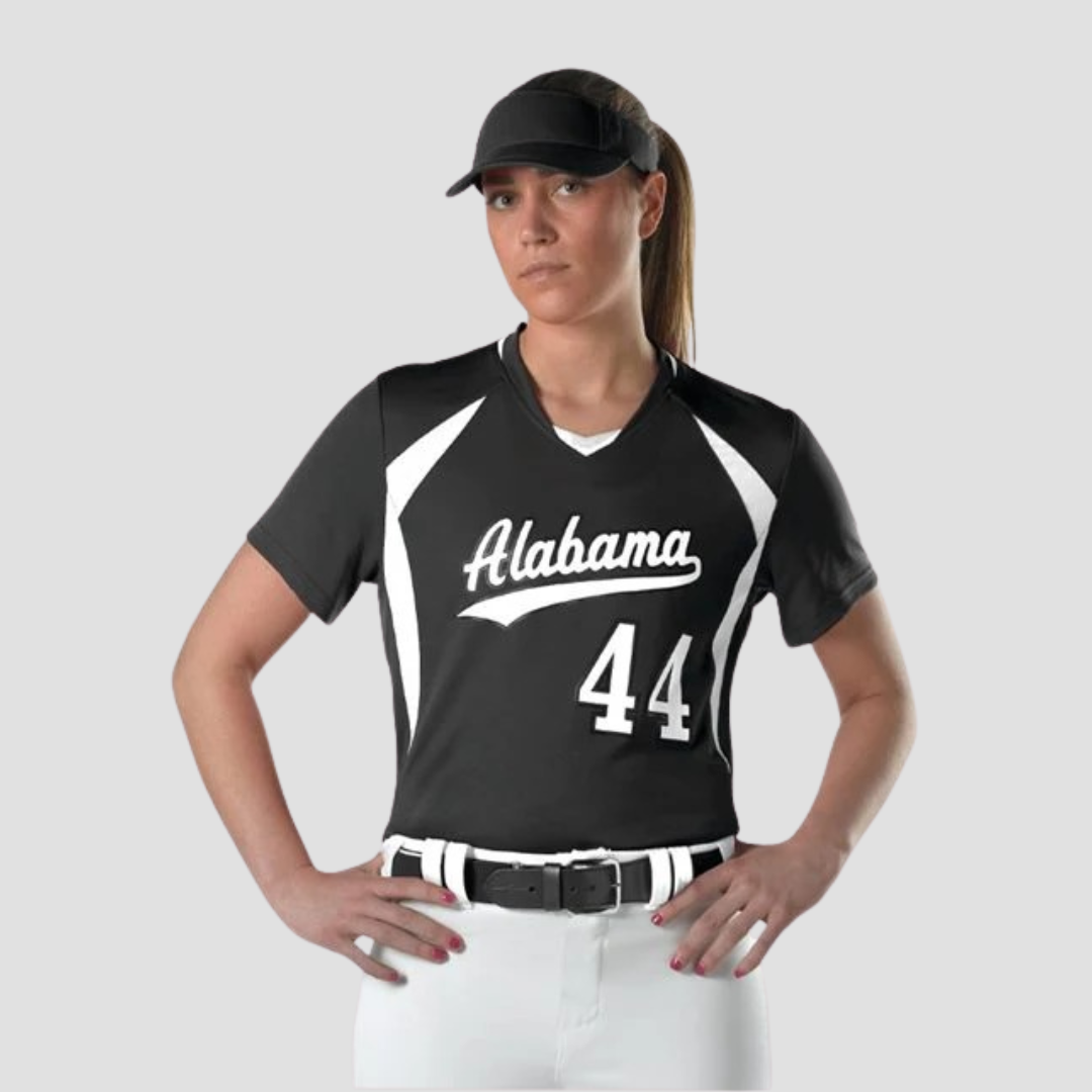 a girl in a softball uniform smiling with her hands on her hips