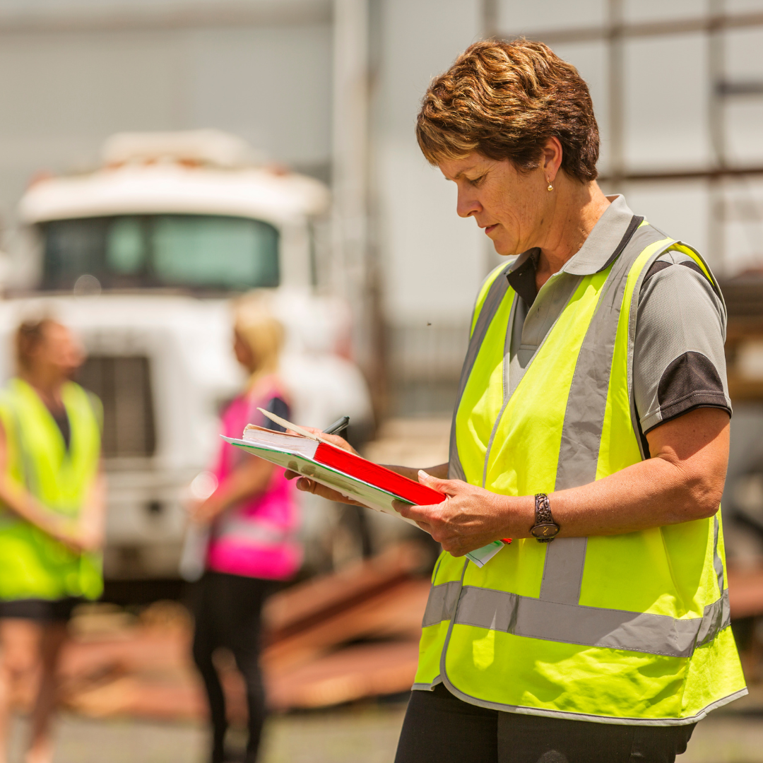a female construction worker in a safety vest looking at clipboard on jobsite
